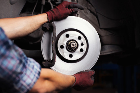 Car mechanic Repairing brakes on car. He is changing brake disc