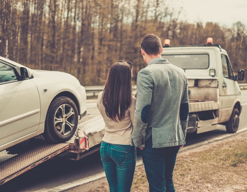 Couple near tow-truck picking up broken car